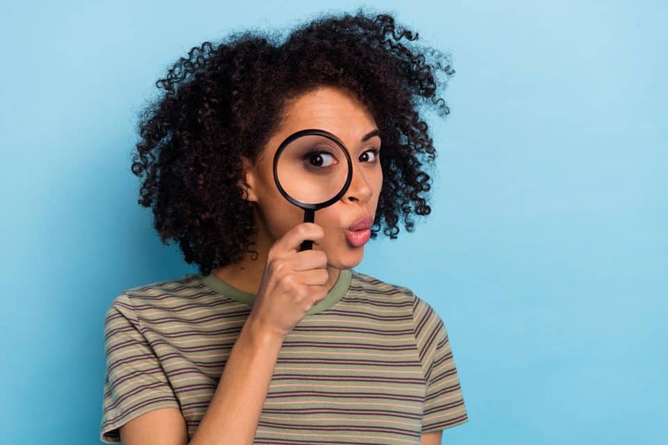 Woman examining details through a magnifying glass, symbolizing omnichannel marketing.
